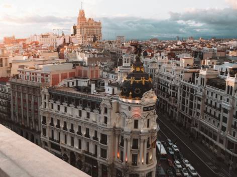 Vista aérea del Edificio Metrópolis en Madrid durante el atardecer, destacando su cúpula dorada.