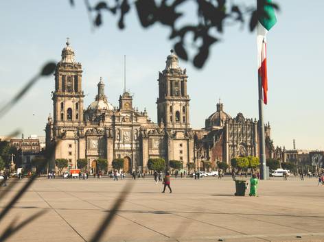 Vista de la Catedral Metropolitana y la Plaza de la Constitución en la Ciudad de México, con una bandera de México ondeando.