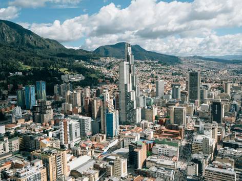 Vista aérea de una ciudad moderna con rascacielos altos y varias construcciones rodeadas por montañas.