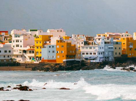 Vista de un pueblo costero con edificios coloridos frente al mar agitado.