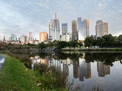 Una vista del horizonte de Melbourne reflejado en el agua durante el amanecer.