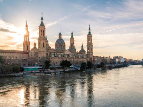 Vista de la Basílica del Pilar en Zaragoza al atardecer, reflejada sobre las aguas del río Ebro.