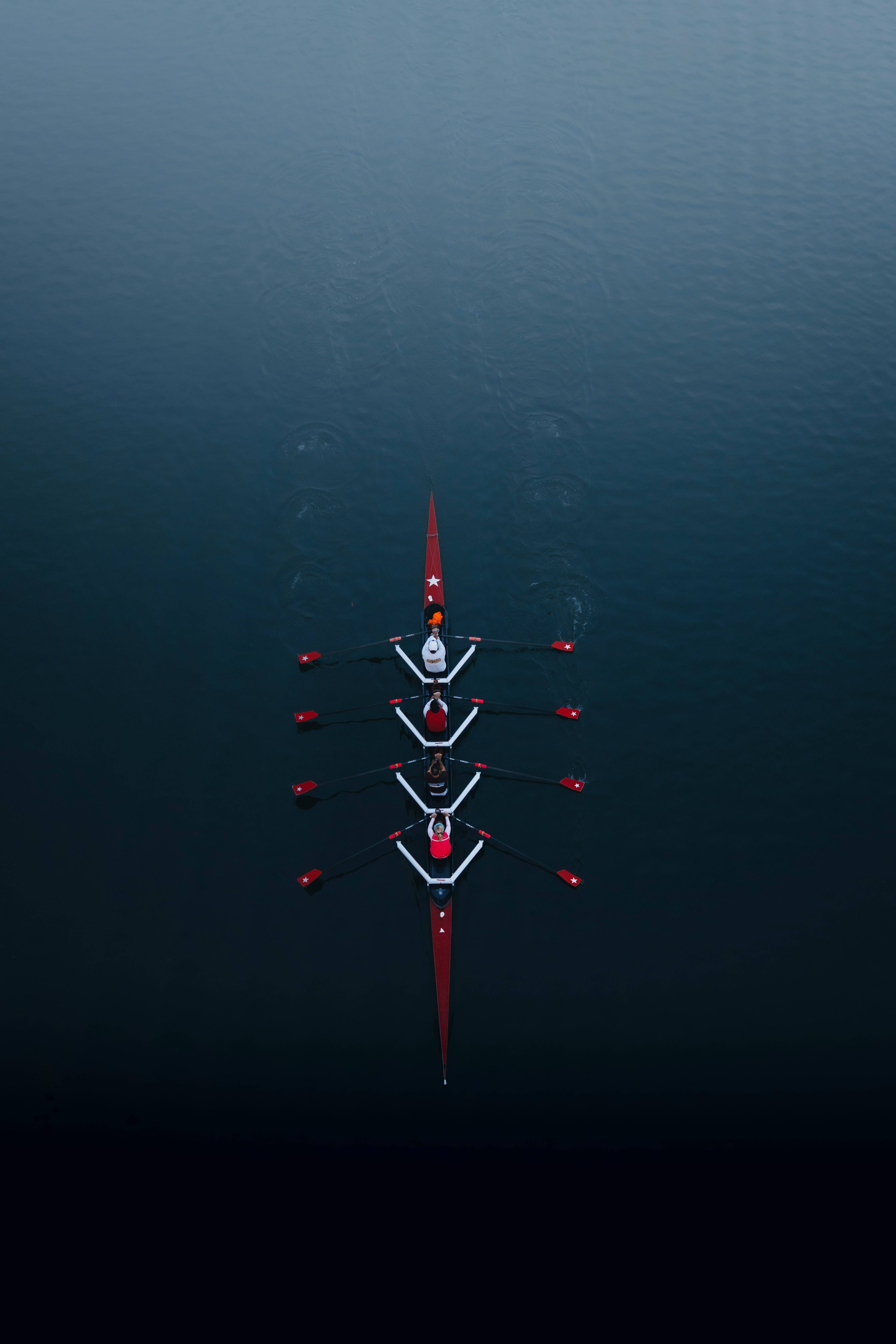 Vista aérea de un grupo de remeros en un bote sobre un agua tranquila.