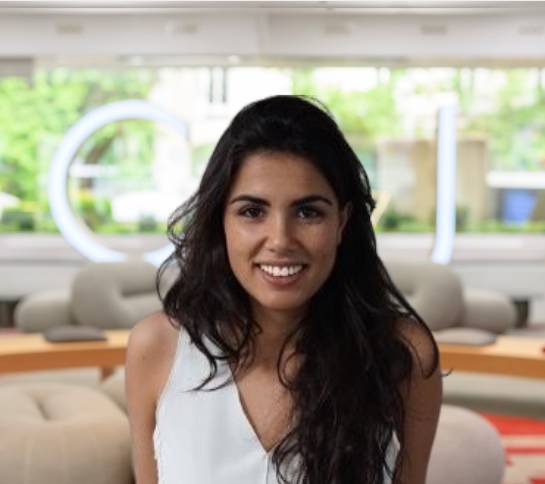 Una mujer sonriente posando en un ambiente moderno y luminoso.