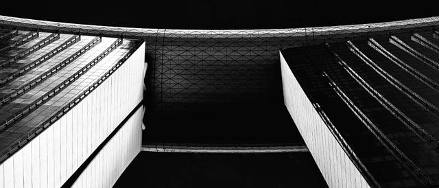 La imagen muestra una vista arquitectónica de un puente entre dos torres, capturada en blanco y negro.