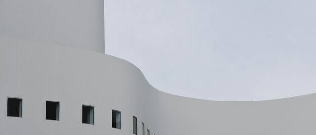 La imagen muestra una estructura arquitectónica moderna con un diseño curvo y paredes blancas.