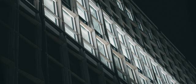 Edificio moderno con ventanas iluminadas en una tarde oscura.