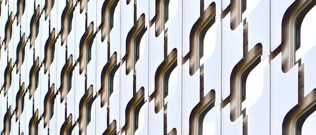 La imagen muestra una pared con un diseño geométrico en tonos blancos y sombras que crean un efecto visual interesante.