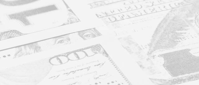 Billetes de dólares americanos apilados sobre una superficie clara.