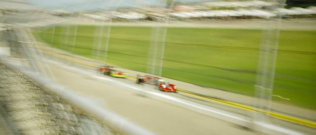 Un par de coches de carrera compitiendo en una pista con un fondo desenfocado.