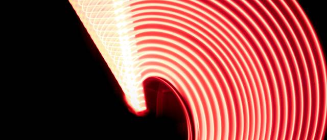 Una serie de luces rojas formando un arco luminoso sobre un fondo oscuro.
