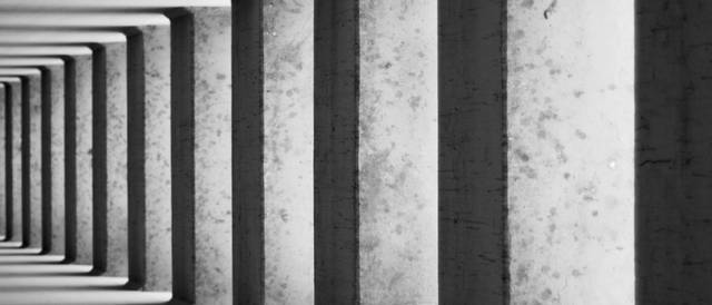 La imagen muestra una serie de columnas en un pasillo con un diseño minimalista.