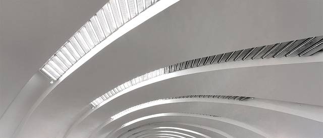 La imagen muestra un diseño arquitectónico moderno con líneas curvas y una iluminación brillante.