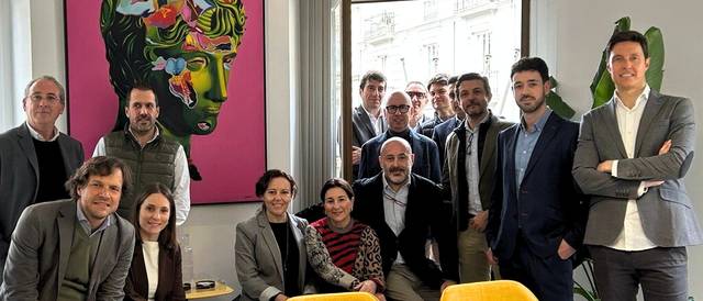 Un grupo de personas se reúne en una sala con un fondo artístico colorido.