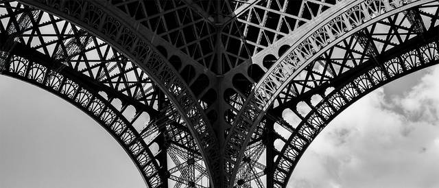 La imagen muestra una vista en blanco y negro de la estructura del Arco de la Torre Eiffel.