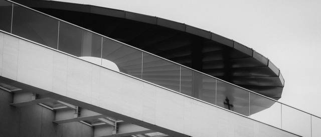 Una estructura arquitectónica moderna con un diseño circular en la parte superior y una figura humana caminando.