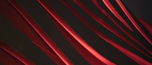 La imagen muestra un diseño abstracto con curvas rojas sobre un fondo oscuro.