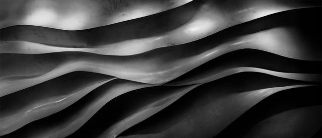 La imagen muestra una serie de ondas en tonos negros y grises que crean un efecto de profundidad y movimiento.