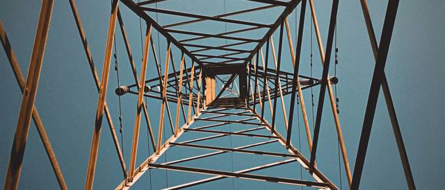 Vista en ángulo bajo de una torre de electricidad contra un cielo azul.