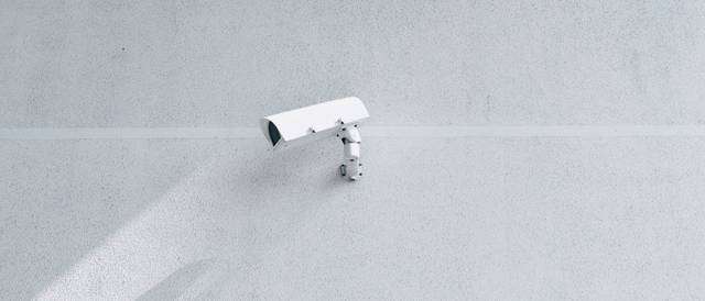 Una cámara de seguridad blanca instalada en una pared clara.