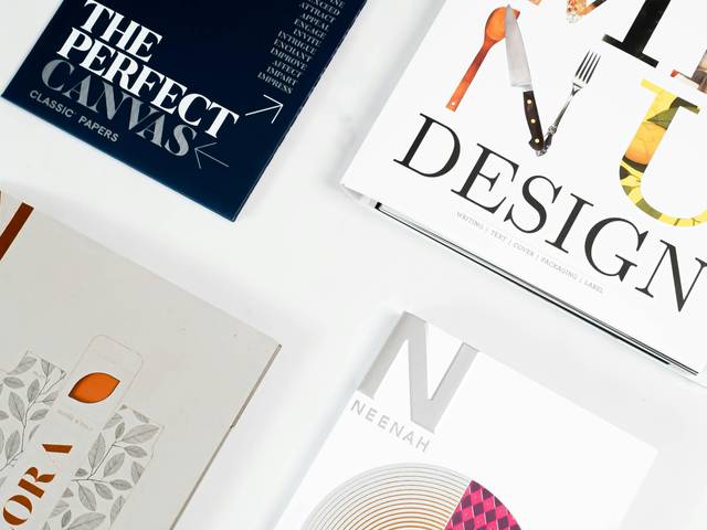 Varias revistas y papeles de diseño están dispuestos en una superficie plana.