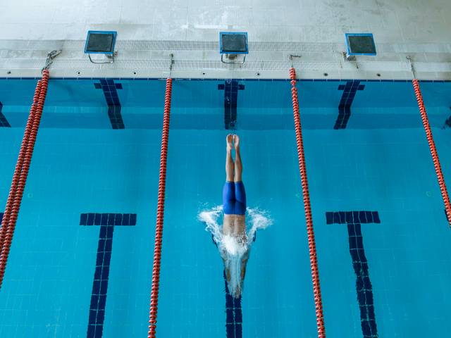 Un nadador se zambulle en una piscina de competición.
