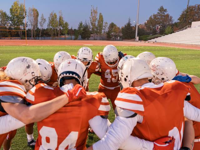 Un grupo de jugadores de fútbol americano se reúne en círculo antes de un partido.