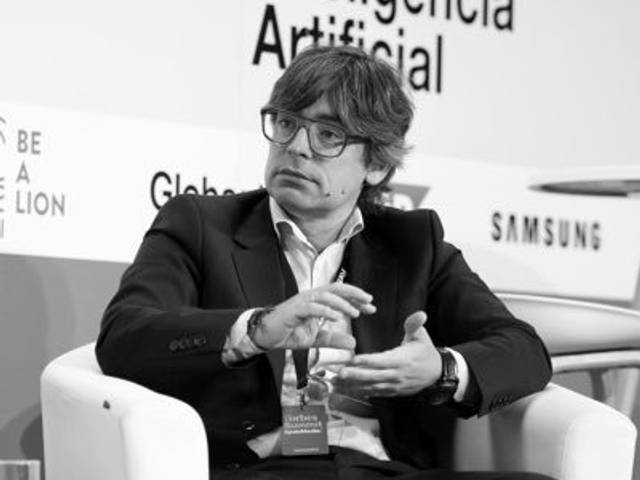 Un hombre con gafas sostiene una conversación en un evento sobre Inteligencia Artificial.