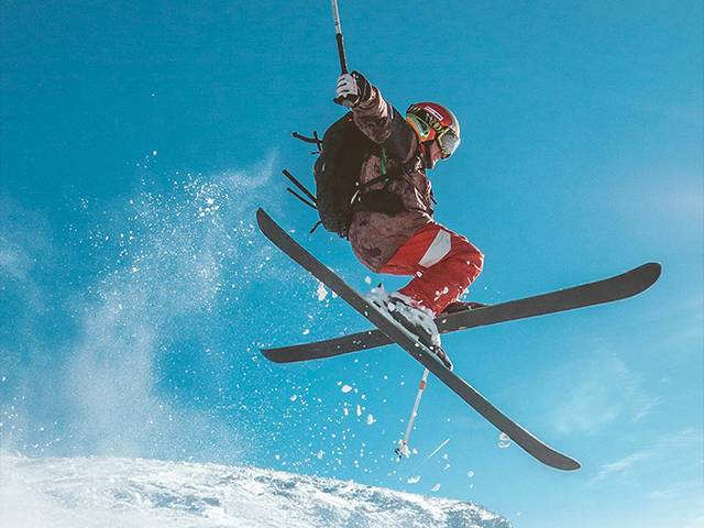 Un esquiador realizando un salto sobre la nieve en una pista de esquí.