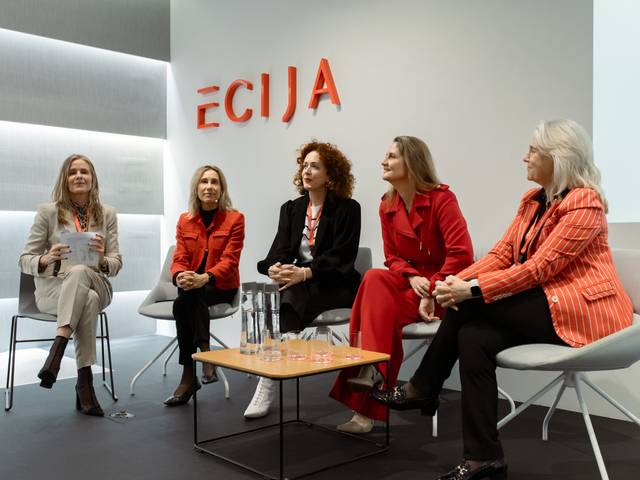 Una mesa redonda con cinco mujeres ponentes en un ambiente moderno y profesional.