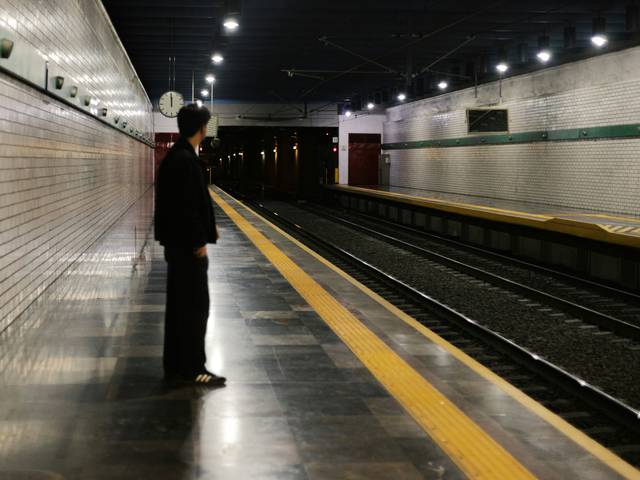 Una persona espera en una estación de metro desierta y luminosa.