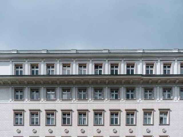 Una fachada de edificio con múltiples ventanas y un cielo nublado de fondo.