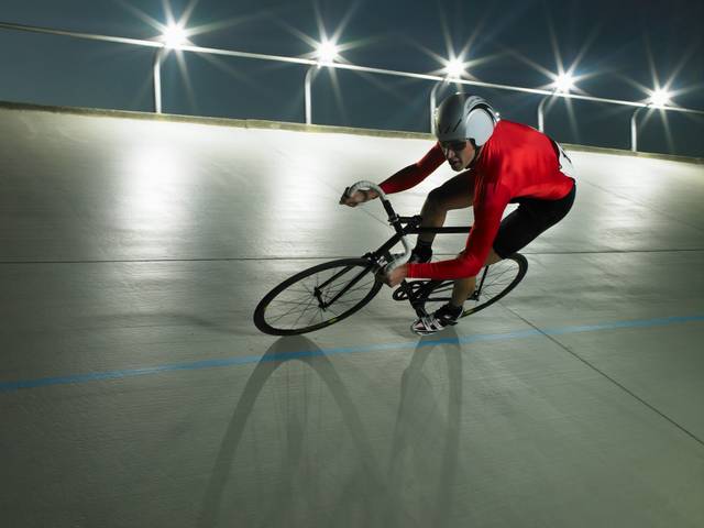 Un ciclista compite en una pista iluminada durante la noche.