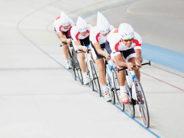 Un grupo de ciclistas compitiendo en una pista de velódromo.