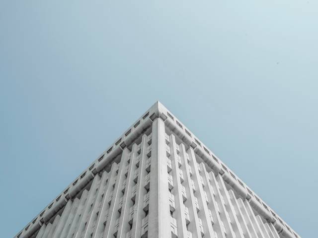 Una imagen que muestra la esquina de un edificio moderno con un cielo claro de fondo.