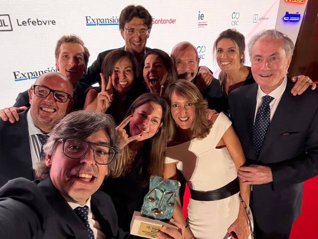 Un grupo de personas sonrientes posan mientras sostienen un premio en un evento social.