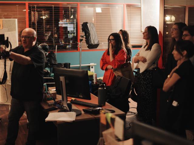 Un grupo de personas observa atentamente a un hombre que les está mostrando algo en un estudio.