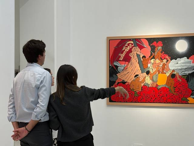 Dos personas observan una pintura en una galería de arte.