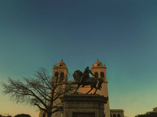 Una estatua de caballo con un jinete frente a dos torres bajo un cielo azul.