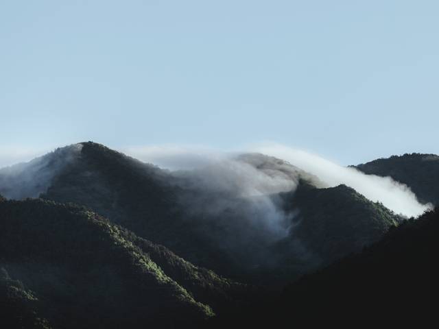 Una vista de montañas cubiertas de neblina bajo un cielo claro.