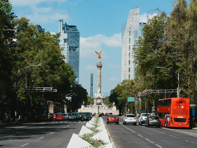 Una vista de una avenida en la Ciudad de México con el ángel de la independencia al fondo.