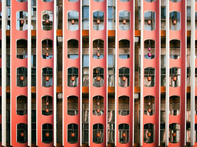 Una fachada arquitectónica colorida con macetas colgadas en ventanas de un edificio.