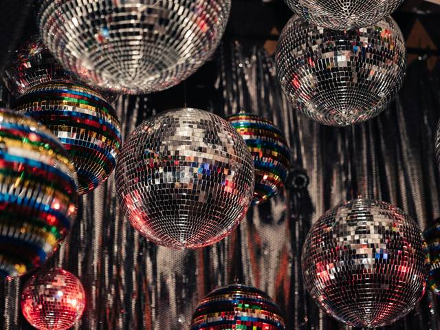 La imagen muestra una colección de bolas de disco brillantes colgando del techo en un ambiente festivo.