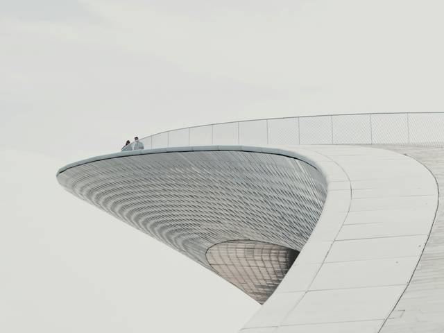 Una pareja de personas se encuentra en la cima de una estructura arquitectónica moderna y curvada.
