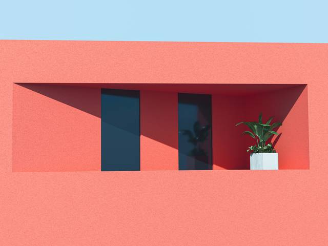 Una fachada moderna de color rojo con ventanas oscuras y una maceta con planta.