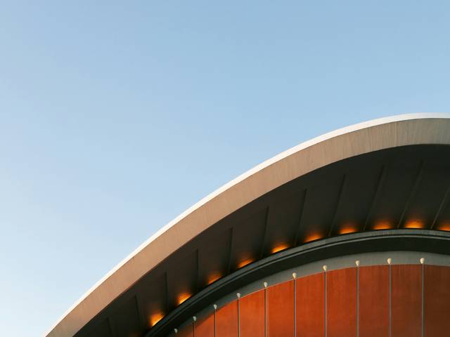 La imagen muestra la parte superior de un edificio con un diseño arquitectónico curvado y una iluminacion suave.
