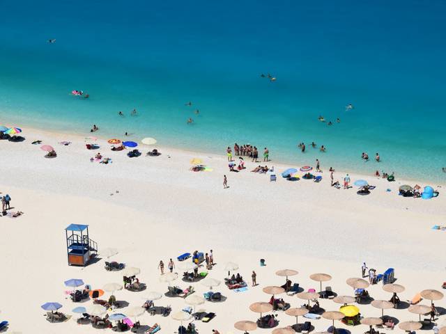 Una vista aérea de una playa llena de gente disfrutando del sol y el mar.