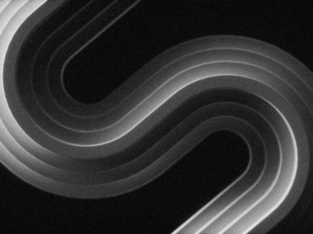 La imagen muestra un diseño abstracto de curvas suaves en tonos oscuros y claros que forman una figura en forma de S.
