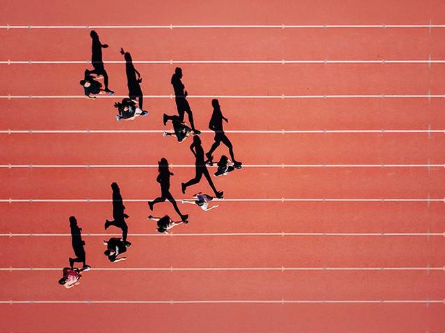 Un grupo de personas caminan sobre una pista de atletismo roja.
