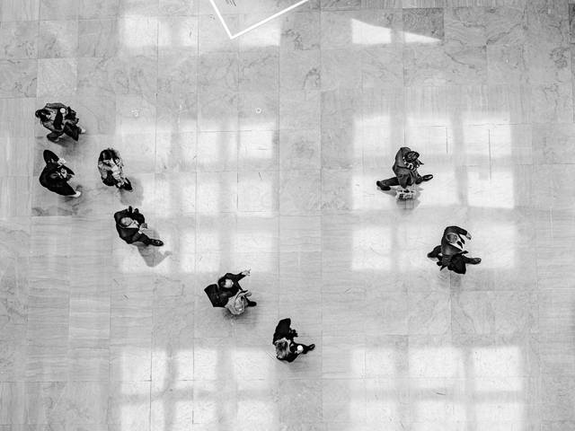 Un grupo de personas camina sobre un suelo de mármol en un gran espacio público.